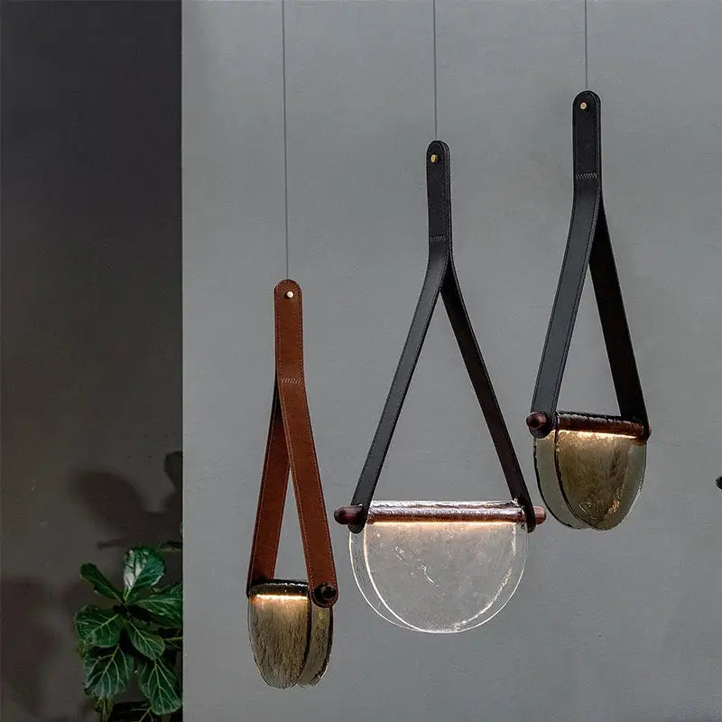 Three modern pendant lamps with decorbites handmade glass amber and matte gray bowls with leather straps in bedroom decor