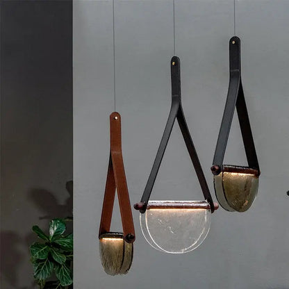 Three modern pendant lamps with decorbites handmade glass amber and matte gray bowls with leather straps in bedroom decor
