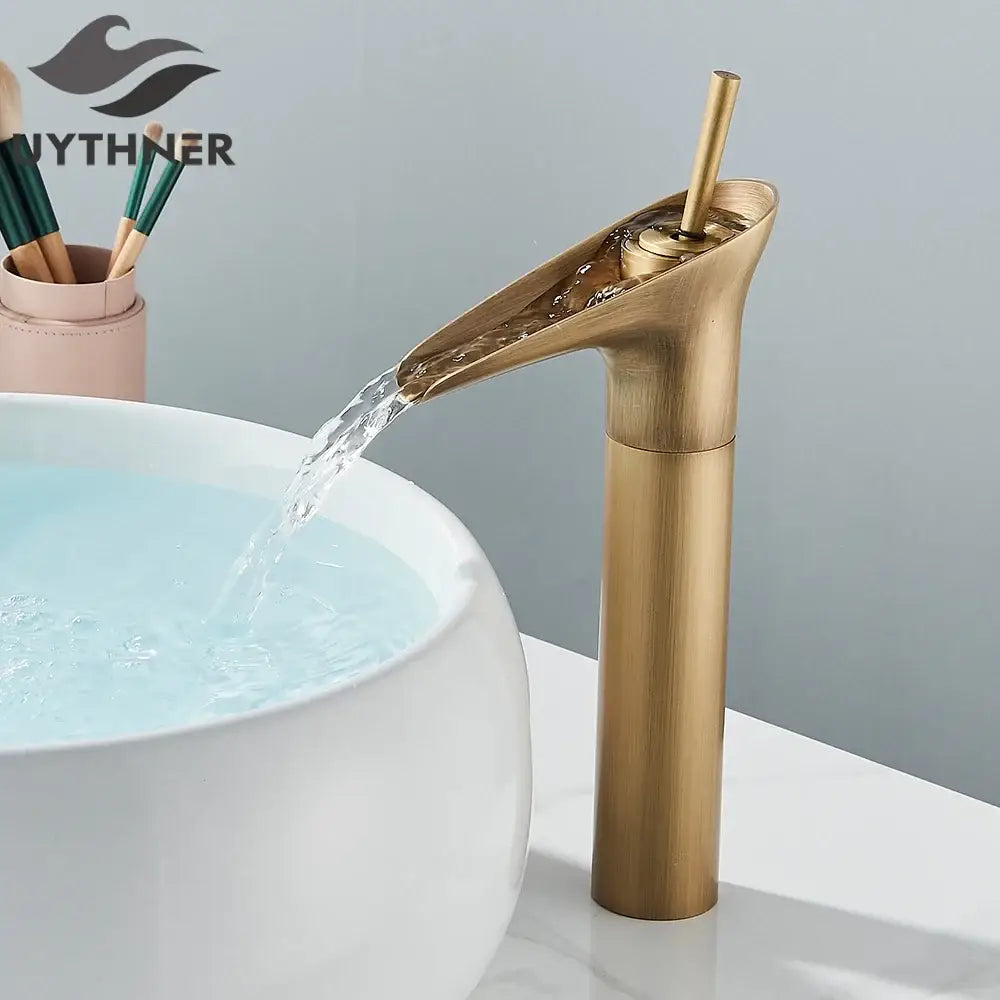Modern antique brass waterfall faucet with cylindrical spout and brass finish flowing water into white ceramic sink