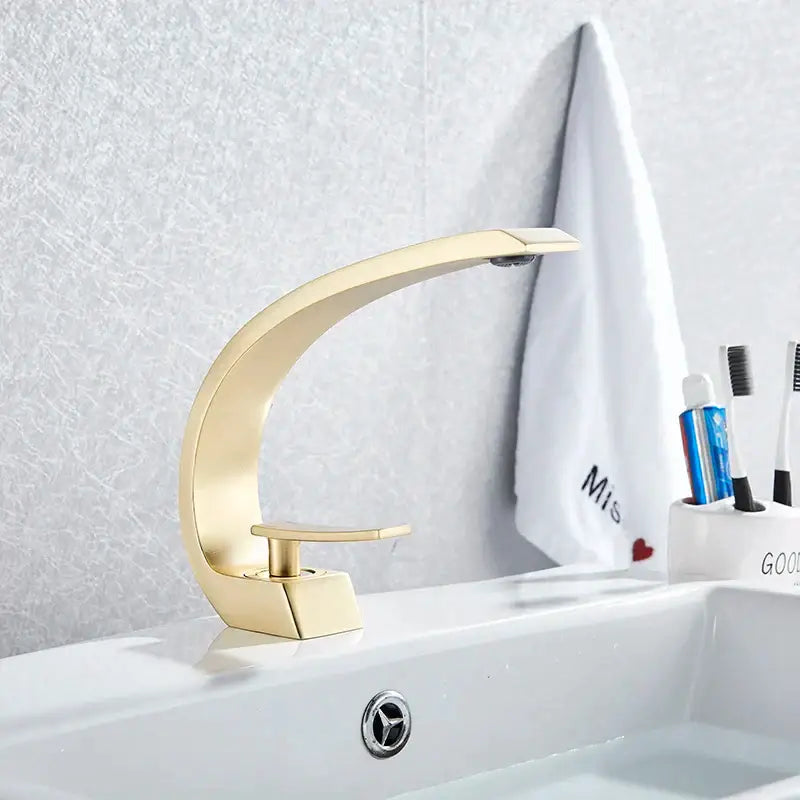 Modern arched brushed gold basin faucet with sleek curved design and brushed metal finish for bathroom use