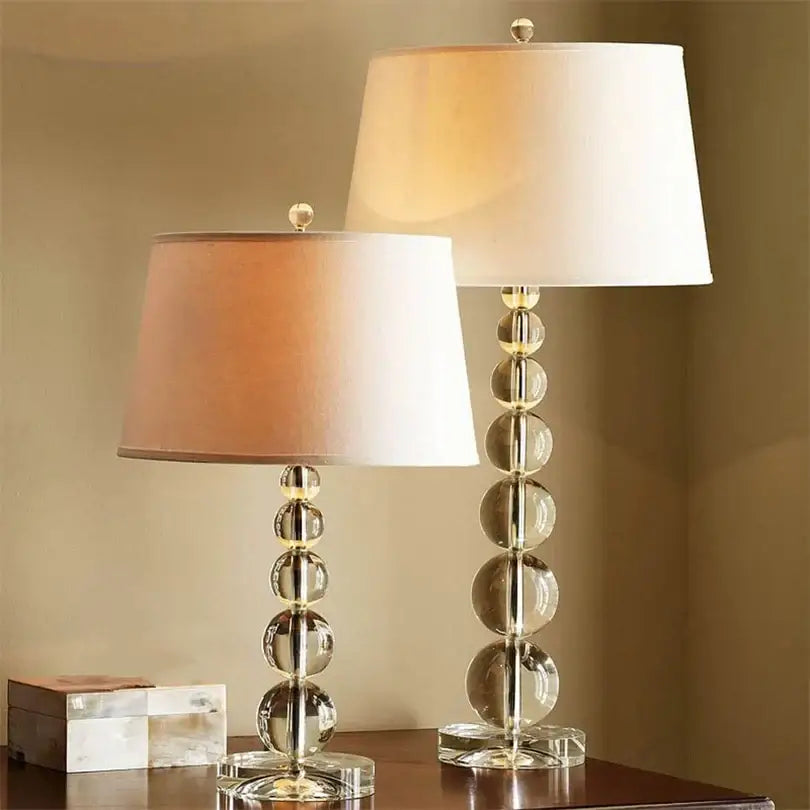 Two elegant decorbites crystal ball table lamps with clear glass bases and soft peach cream fabric shades for bedroom decor