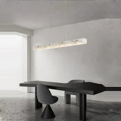 A modern art deco marble steel chandelier in black and gold featuring a sleek translucent white marble body above dining table