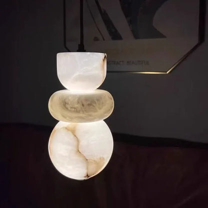 A modern pendant light with three stacked white and beige onyx orbs featuring spanish marble for alabaster indoor ceiling decor