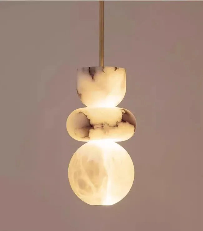 A modern pendant light with three warm-toned alabaster indoor ceiling orbs featuring natural spanish marble veining