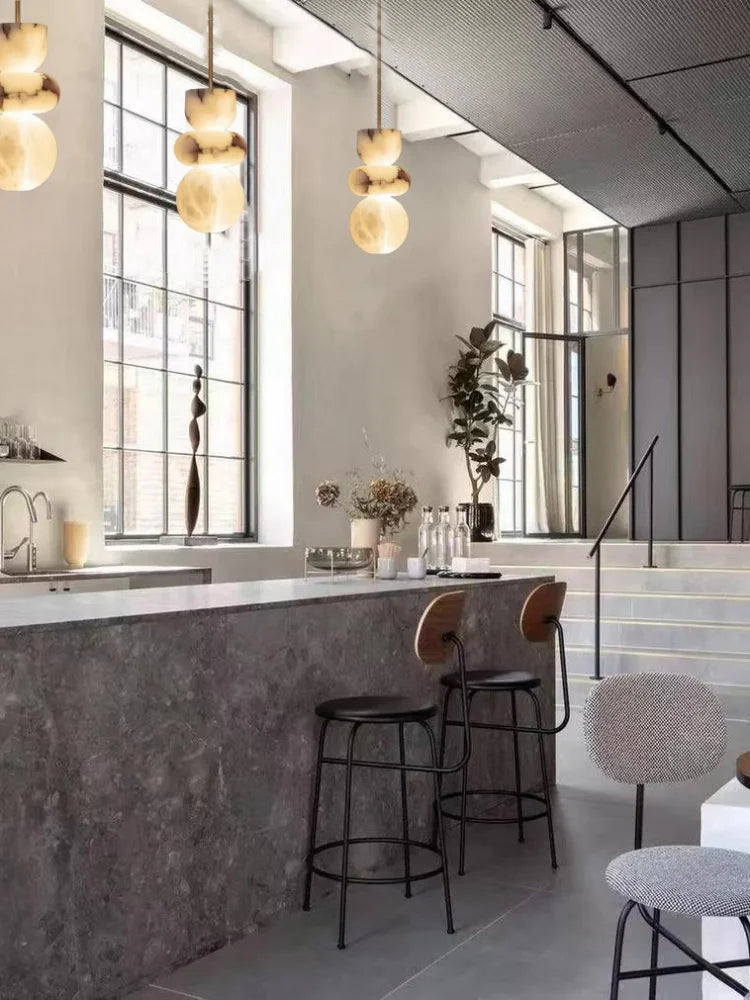 Dark gray spanish marble countertop with smooth polished surface and subtle veining in a minimalist alabaster indoor ceiling chandelier setting