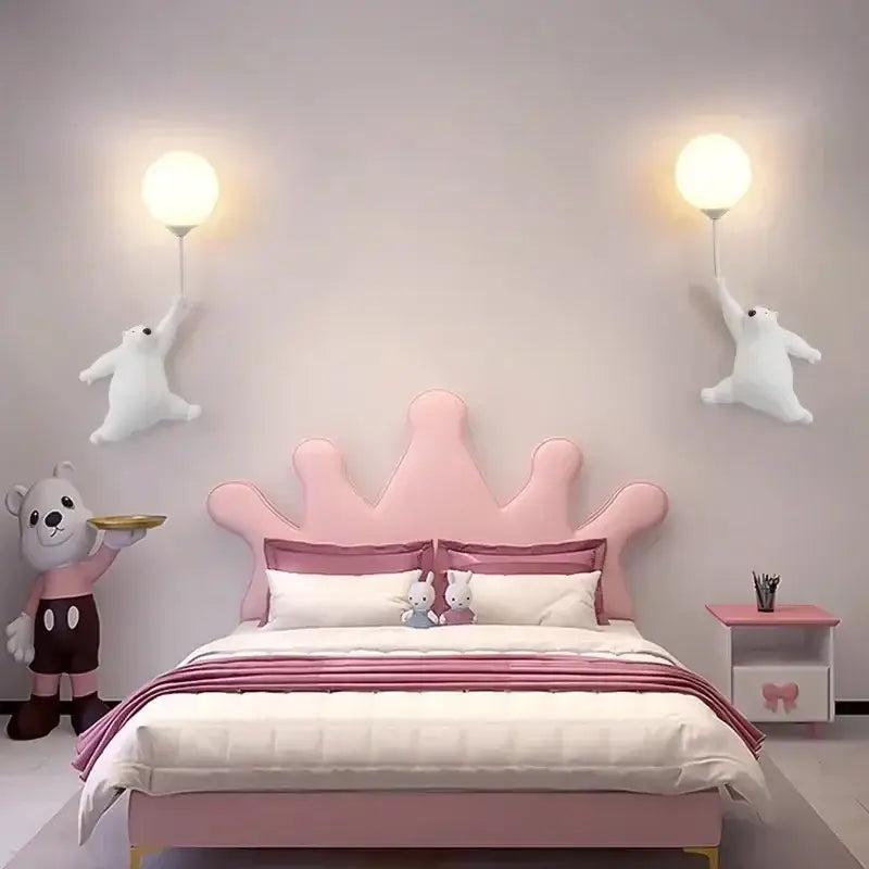 Pink crown-shaped headboard and bed frame with soft fabric upholstery next to modern bear moon wall lamp for kids bedroom decor