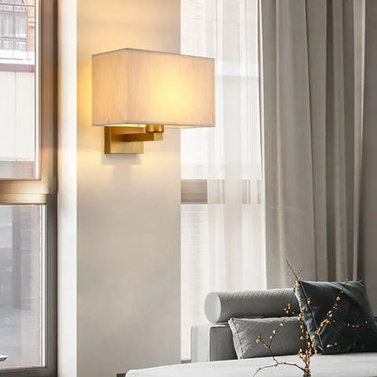 Gold-finished rectangular wall lamp with soft beige fabric shade for an elegant bedroom wall lamp setup