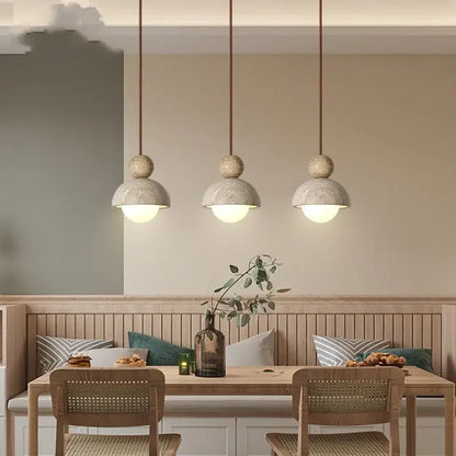 Three decorbites led pendant lights with matte concrete shades and warm cords hang above a wooden dining table