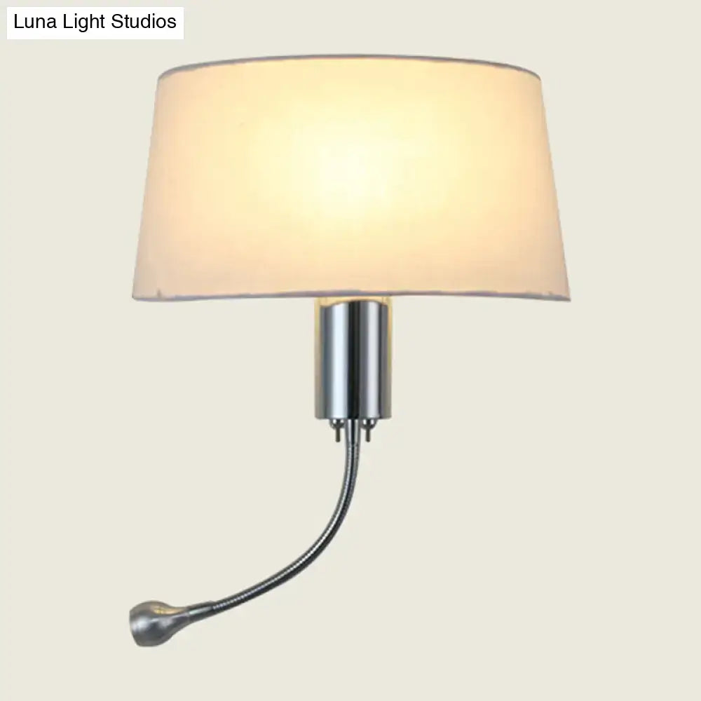 A sleek, modern wall-mounted lamp with a cylindrical chrome base and an adjustable gooseneck arm ending in a small spotlight head.