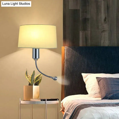 A modern beige fabric flush wall sconce with a curved metallic arm and soft cream shade for bedroom reading light