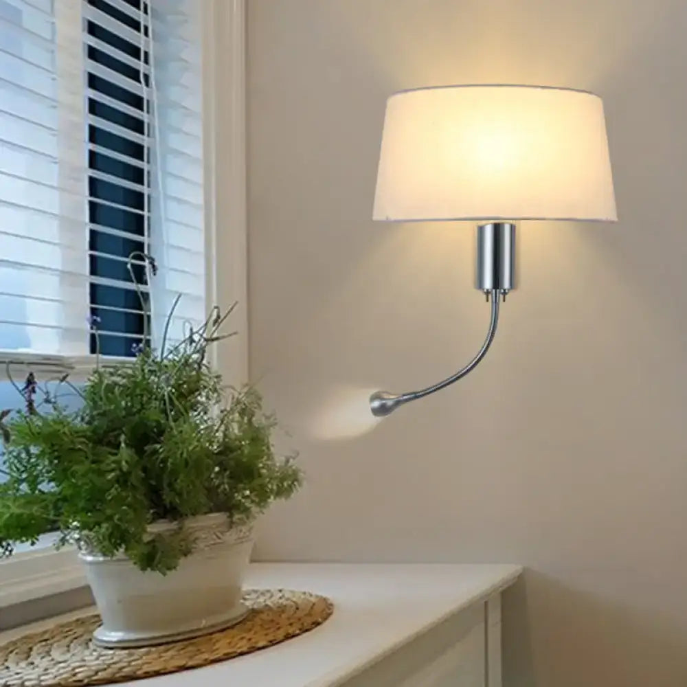 A sleek, curved chrome wall sconce with a soft white fabric shade.