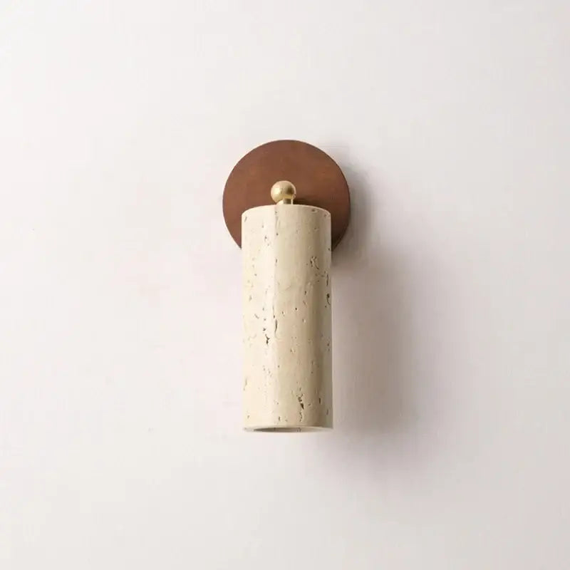 Modern beige stone and bronze wall light fixture with cylindrical speckled sconce and brass sphere for bedroom use