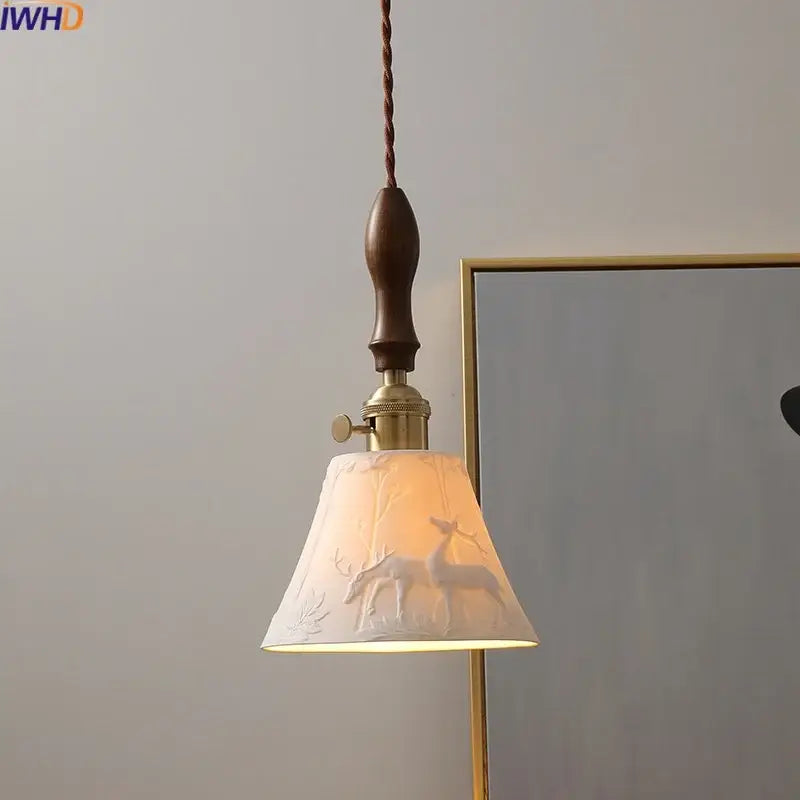 A warm-toned ceramic led pendant light with embossed deer decor hangs from a brass fixture and twisted cord