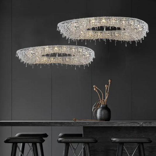 Two elegant circular bird nest crystal pendant chandeliers with cascading droplets hang in a modern living room