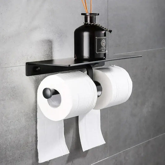 Modern black aluminum double toilet paper holder with shelf mounted on wall holding two white rolls of toilet paper
