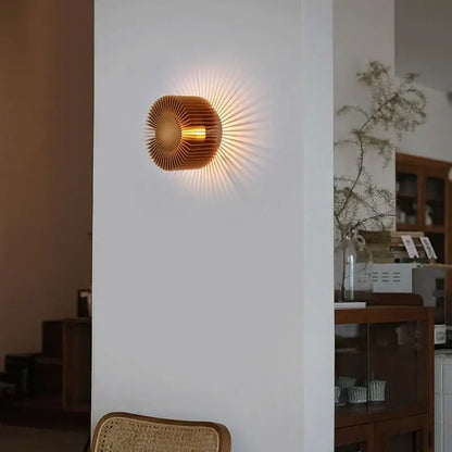 Golden sunburst wall sconce with radiating metallic rays in elegant black aluminum wall sconce for living room use