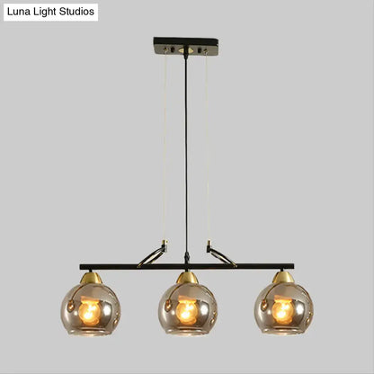 Modern black metal chandelier with three smoke gray glass globe shades and brass accents for hall island lighting