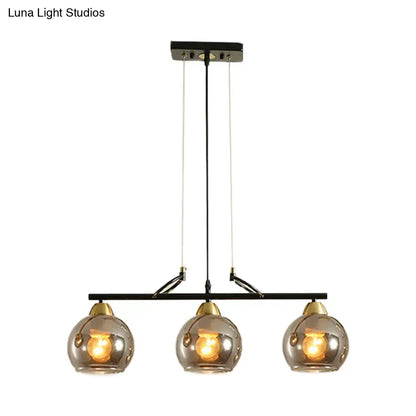 Modern black metal chandelier with three smoke gray glass globes and brass accents for hall island lighting