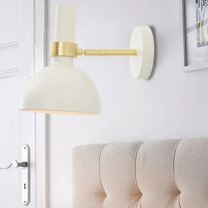 Cream-colored wall lamp with brass-finished arm and mounting plate as a modern domed wall lamp for bedroom use
