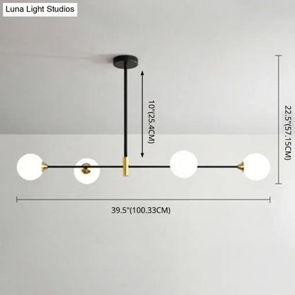 Modern black metal island pendant with brass accents and four frosted glass globe bulbs featuring adjustable chain cord length