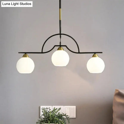 Decorbites modern island light fixture with black finish metal frame and cream clear glass globe shades with gold accents