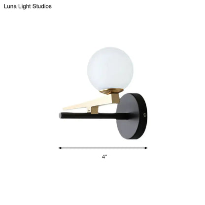 Modern black and brass wall sconce with a frosted white glass ball shade for bedroom lighting