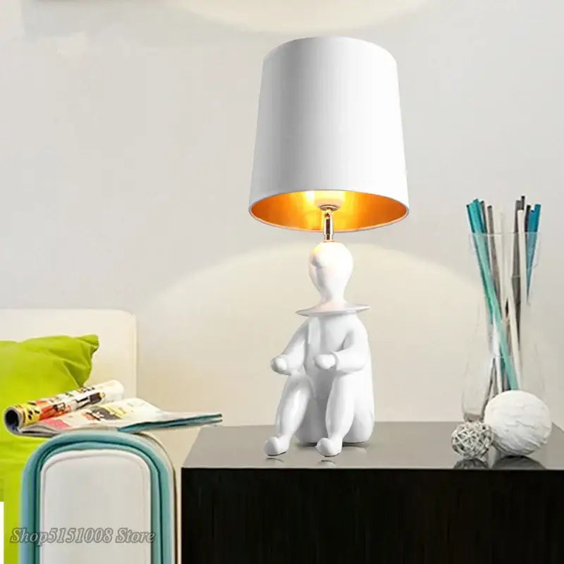 Modern black and gold ceramic clown desk lamp with white seated figurine base and orange interior shade decorbites clown desk