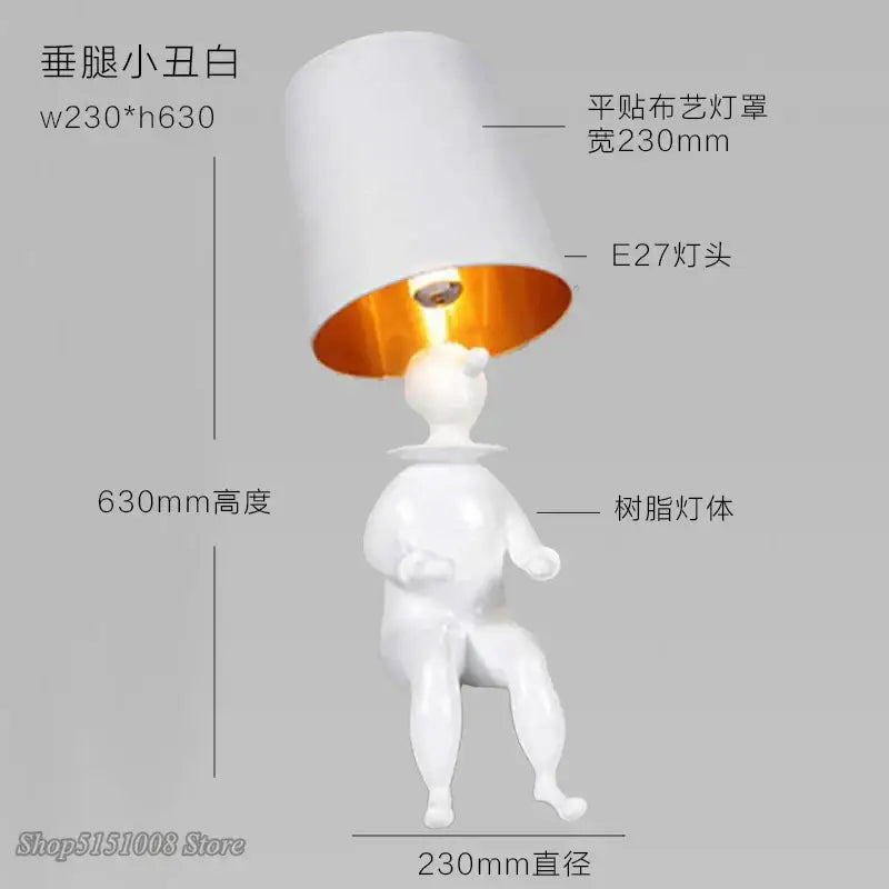 Modern black and gold ceramic clown desk lamp with white resin figurine body and cylindrical white fabric shade with orange interior decorbites clown desk