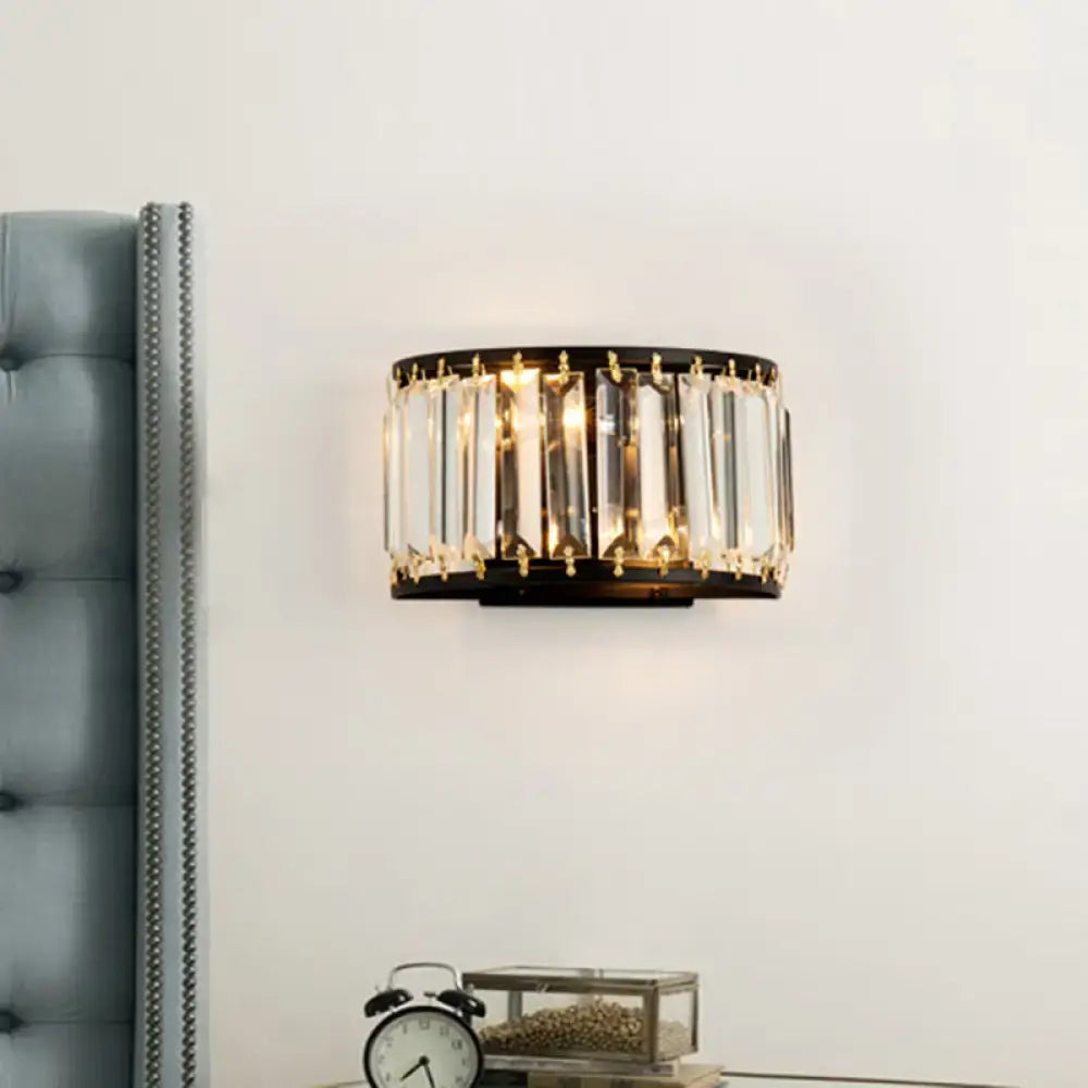A modern black and gold wall lamp with vertical crystal prisms designed as a bedroom light fixture
