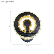 Modern black and gold crystal wall sconce with warm white light featuring omega-shaped fixture and clear crystal accents