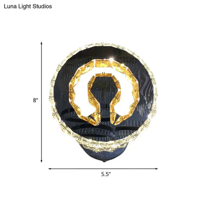 Modern black and gold crystal wall sconce with warm white light featuring omega-shaped fixture and clear crystal accents