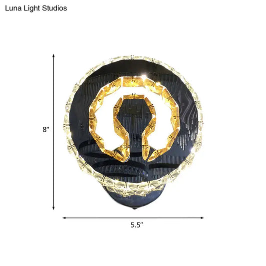 Modern black and gold crystal wall sconce with warm white light featuring omega-shaped fixture and clear crystal accents