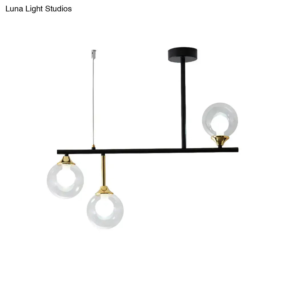 Modern black and brass DecorBites™ island chandelier with three clear glass ball shades for dining room lighting