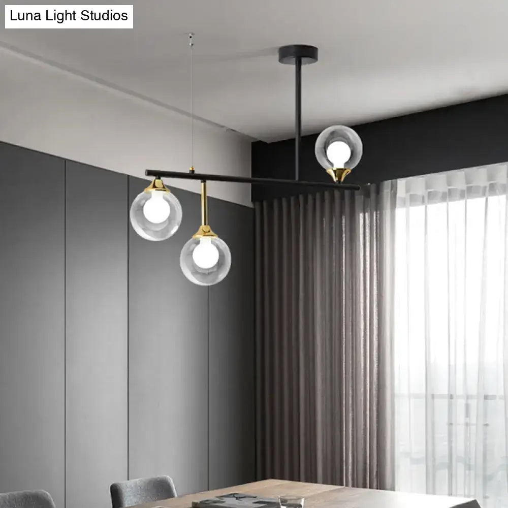 Modern black metal pendant light fixture with three clear glass globes and gold accents for dining room