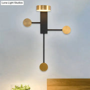 Modern black and gold wall sconce with a minimalist black frame and three gold circular accents with LED top light