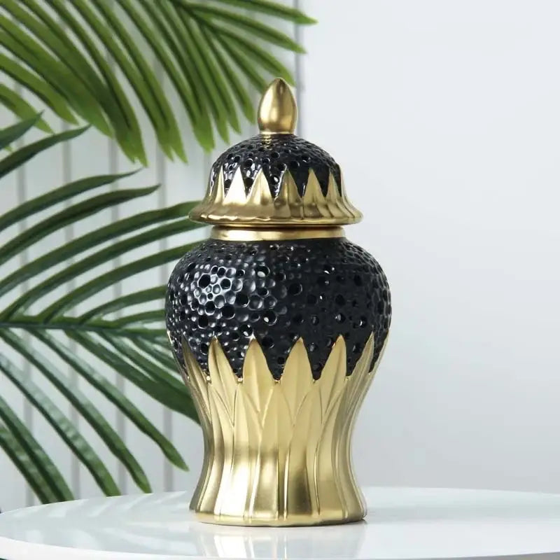 Modern black and golden porcelain jar with textured perforated body and ornate leaf-inspired base for living room decor