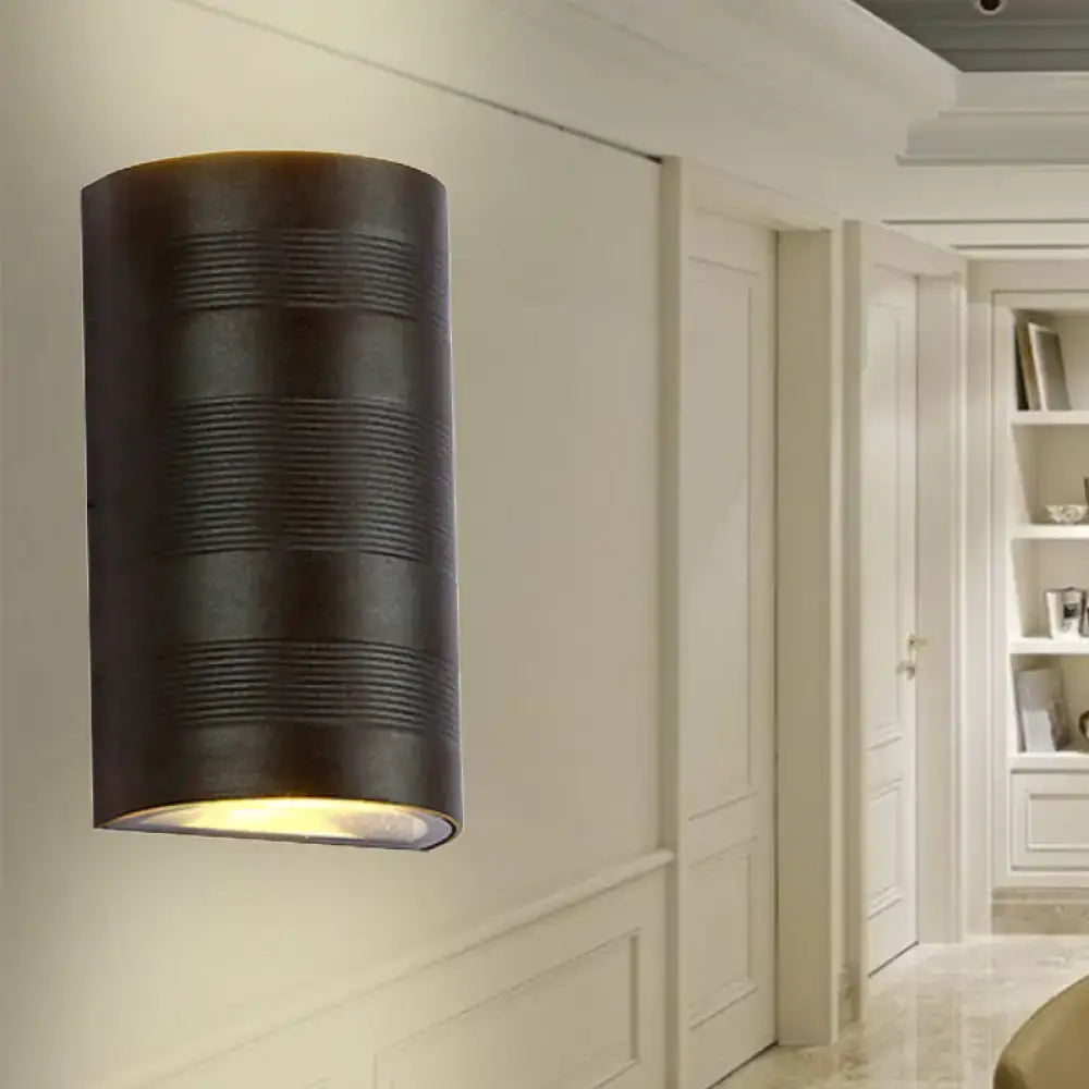 Dark bronze cylindrical wall lamp with horizontal ribbed texture and warm white downward-facing light for outdoor use