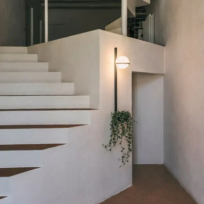 Modern black and white acrylic ball wall lights with warm glow mounted on sleek black arm by minimalist white staircase