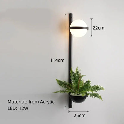 Modern black iron wall lights with a white acrylic ball shade and integrated planter for bedroom decor