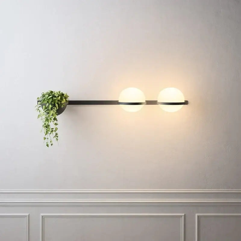 Modern black metal wall lights with white acrylic ball shades and an integrated hanging plant holder for bedroom use