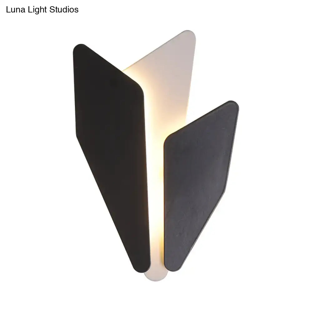Modern black and white geometric leaf-shaped wall light fixture with warm glowing light for living room decor