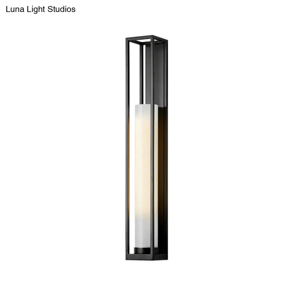 Modern black and white glass tubular wall mount light featuring a frosted glass panel emitting warm diffused light