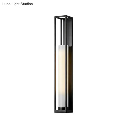 Modern black and white glass tubular wall mount light featuring a frosted glass panel emitting warm diffused light