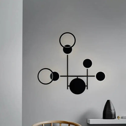 Modern black and white metallic round led wall sconce with black geometric interconnected circles on gray background