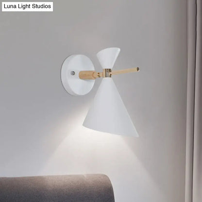 White conical wall sconce with natural wood arm and brass accents featuring modern black angle shade for bedroom lighting