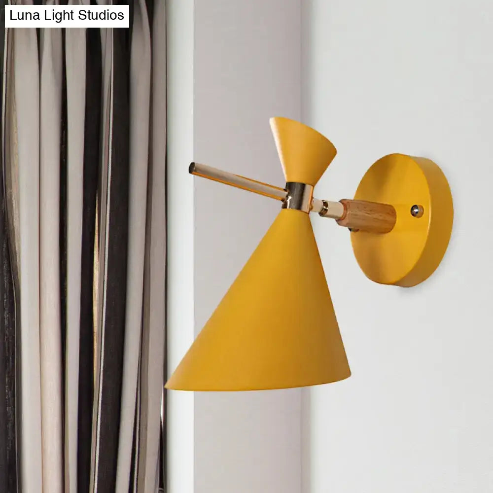 Modern yellow conical wall sconce with wooden arm and metallic joint featuring an angle shade for bedroom lighting
