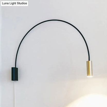 A sleek black and brass arched led wall mount light with minimalist design for modern living room use