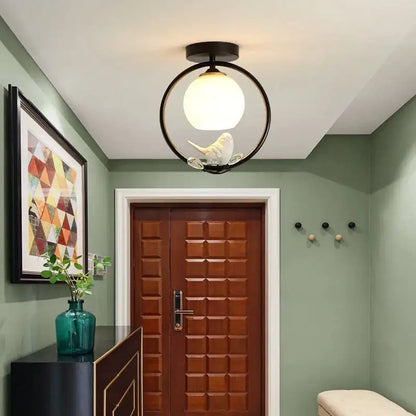 Modern black ceiling light fixture with frosted glass globe and white bird figurine for corridor entrance lighting