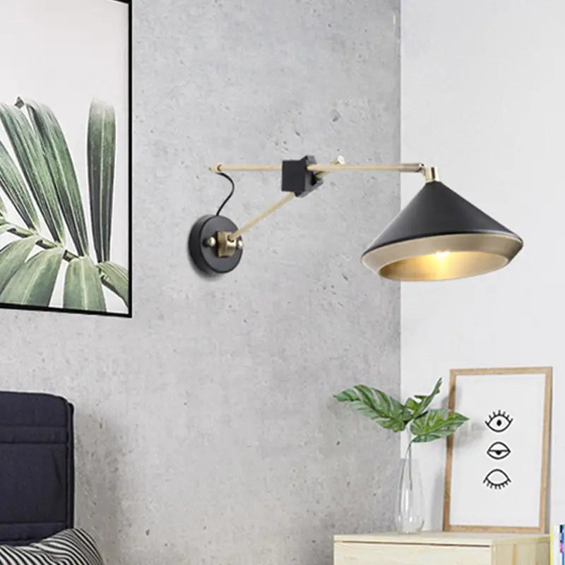 Modern black and brass wall light with adjustable arm and conical shade featuring a visible bulb base for bedroom use