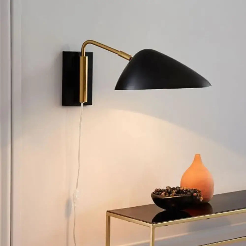 Modern black and brass wall lamp with curved arm conical shade and articulated fixture height for bedroom lighting